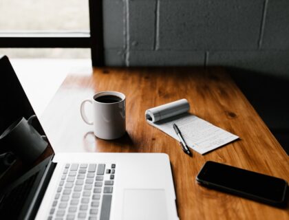 MacBook Pro, white ceramic mug,and black smartphone on table