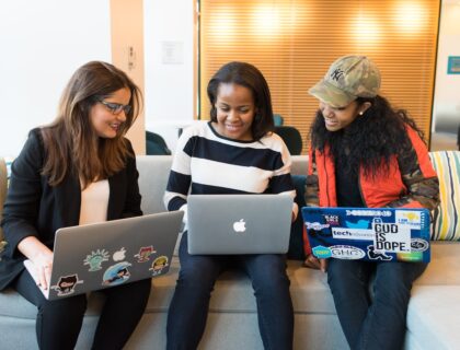 three women sitting on sofa with MacBook