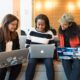 three women sitting on sofa with MacBook